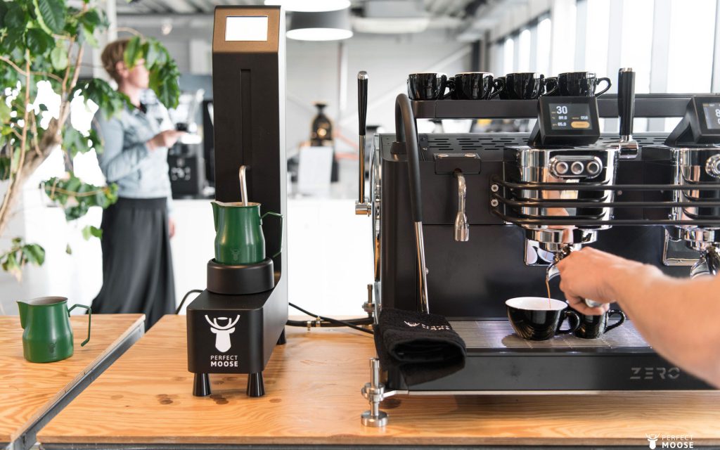 A barista is using the black Perfect Moose milkfoamer for a coffee order. Photo by Perfect Moose